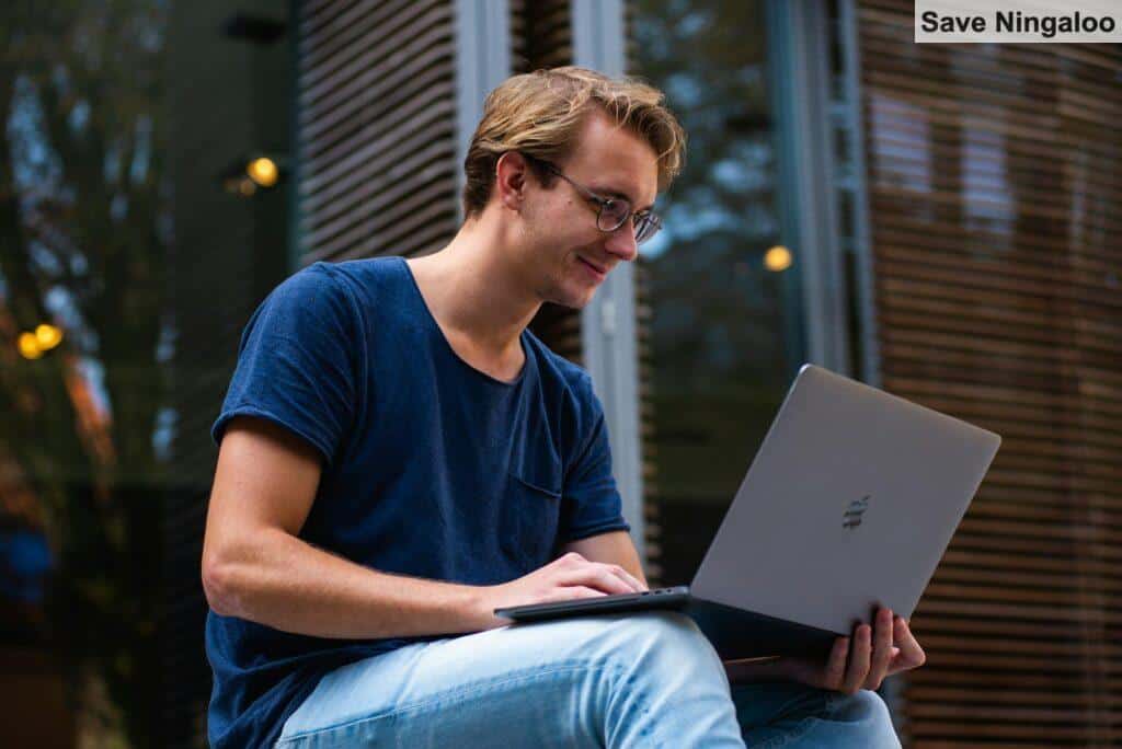 A young man sitting outdoors in Leiden, Netherlands, working on a laptop.